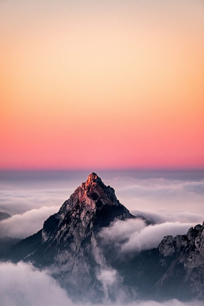 Mountain peak above the clouds with sunset in the background, the mountains we must climb on our hero's quest