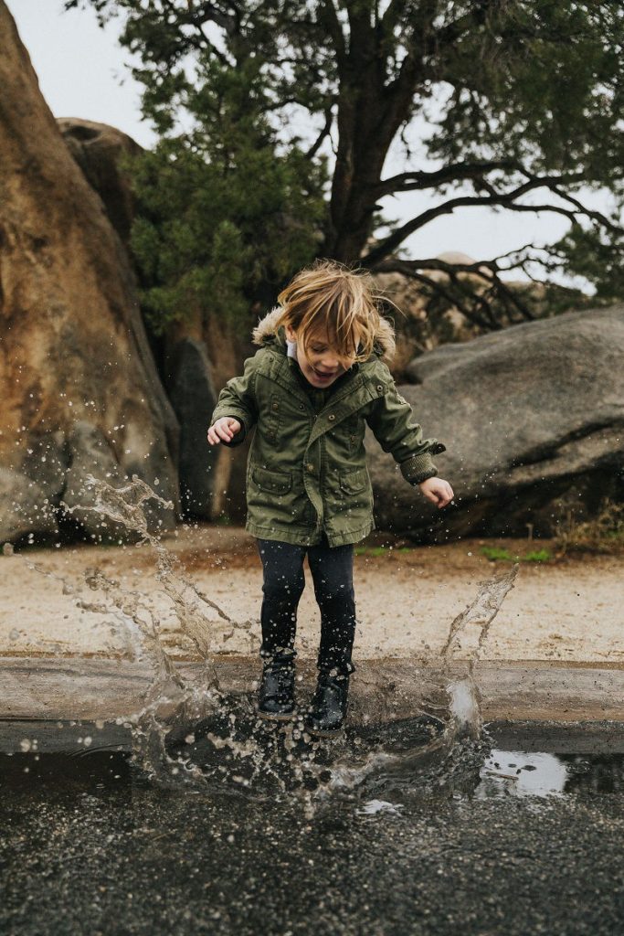A child splashing in a puddle, living fully in the moment, mindfully